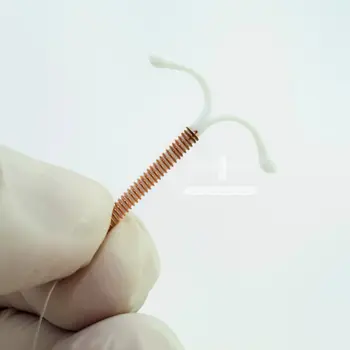 Latex gloved hand holding an intrauterine device (IUCD or Copper T)